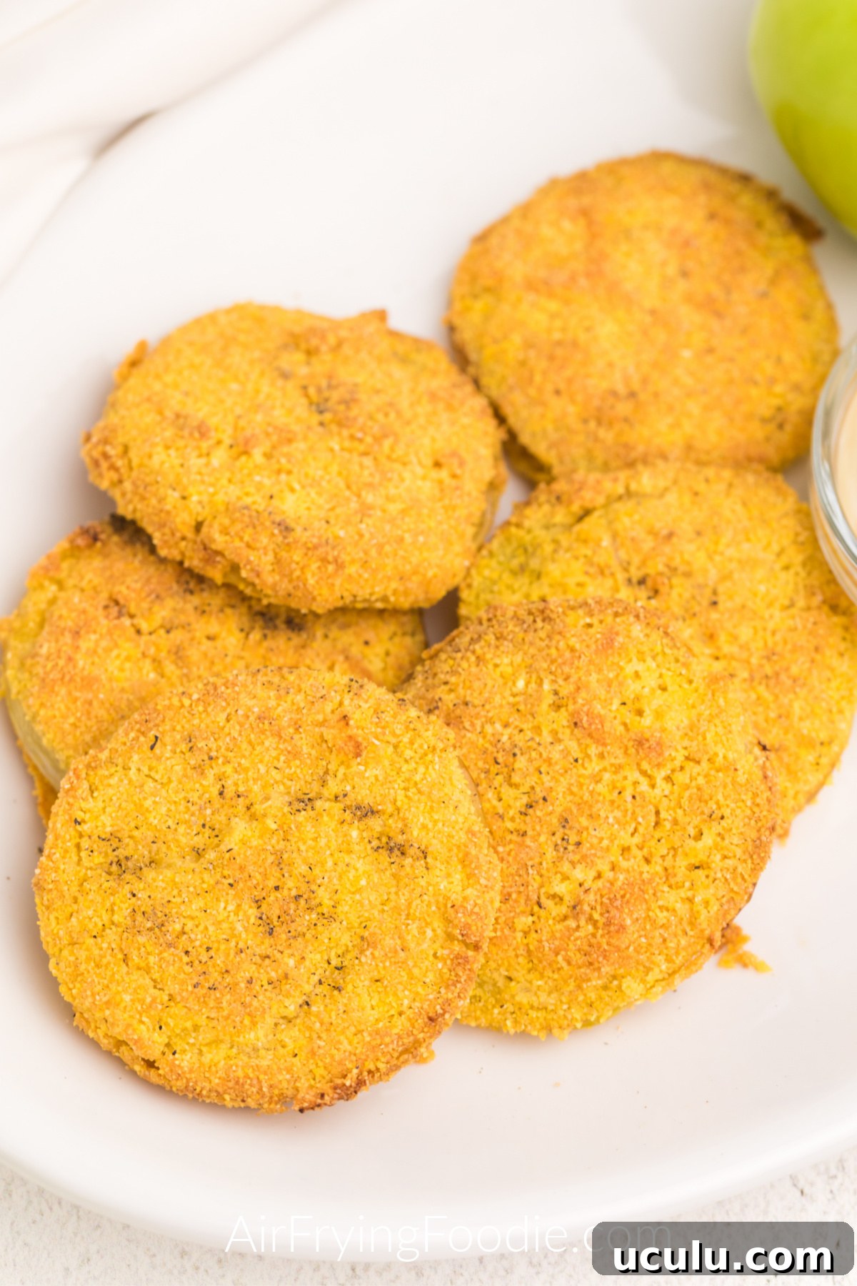 Close up photo of air fryer fried green tomatoes on a white plate with dipping sauce, ready to be served.