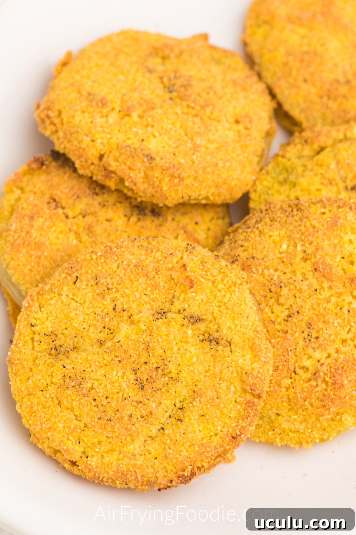 Close up of fried green tomatoes made in the air fryer and served on a white plate, ready to eat.