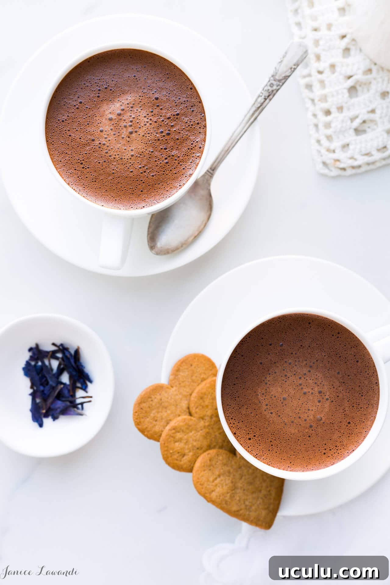 Overhead shot of two cups of hoomemade hot chocolate made with just 2 ingredients: chocolate and milk, and served with heart-shaped cookies.