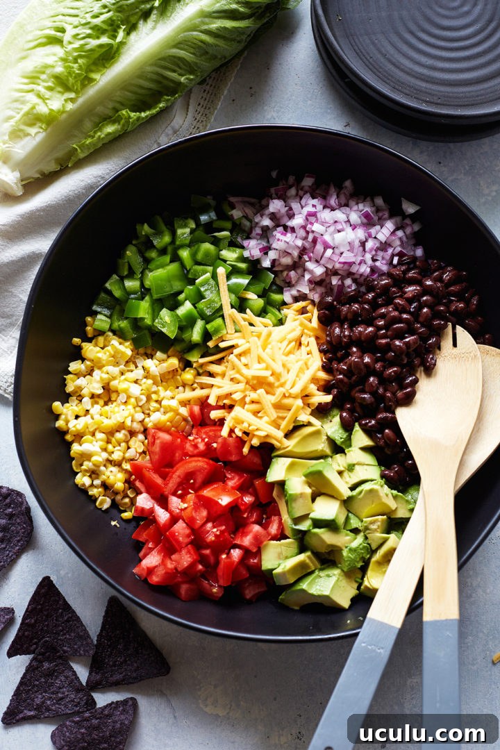ingredients needed to make a veggie taco salad in a black bowl