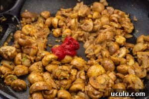 Indian Mushroom Bhaji Recipe | Flavorful Mushroom Curry Guide 11 Tomato puree added to the to the mushroom bhaji cooking in a frying pan