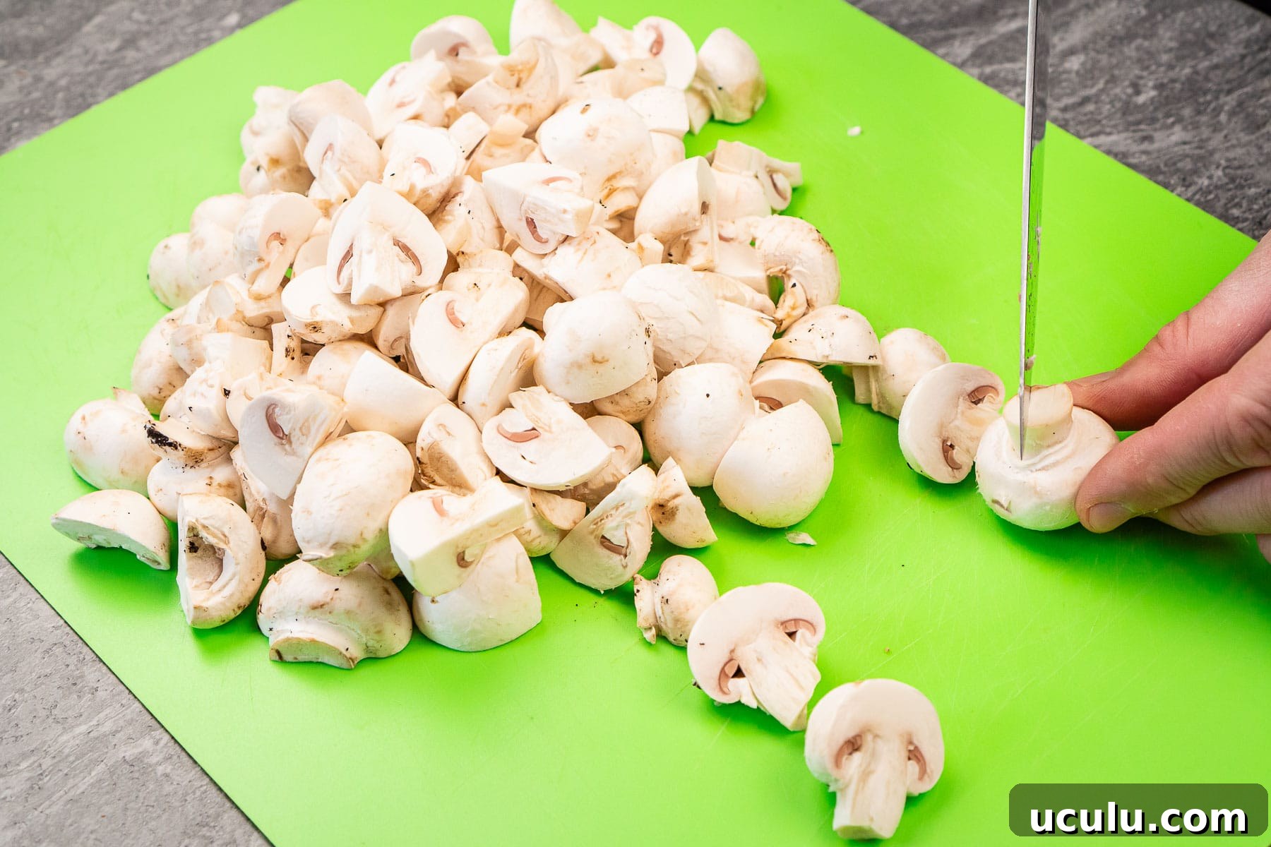Indian Mushroom Bhaji Recipe | Flavorful Mushroom Curry Guide 14 Chopping up closed cup mushrooms on a green chopping board