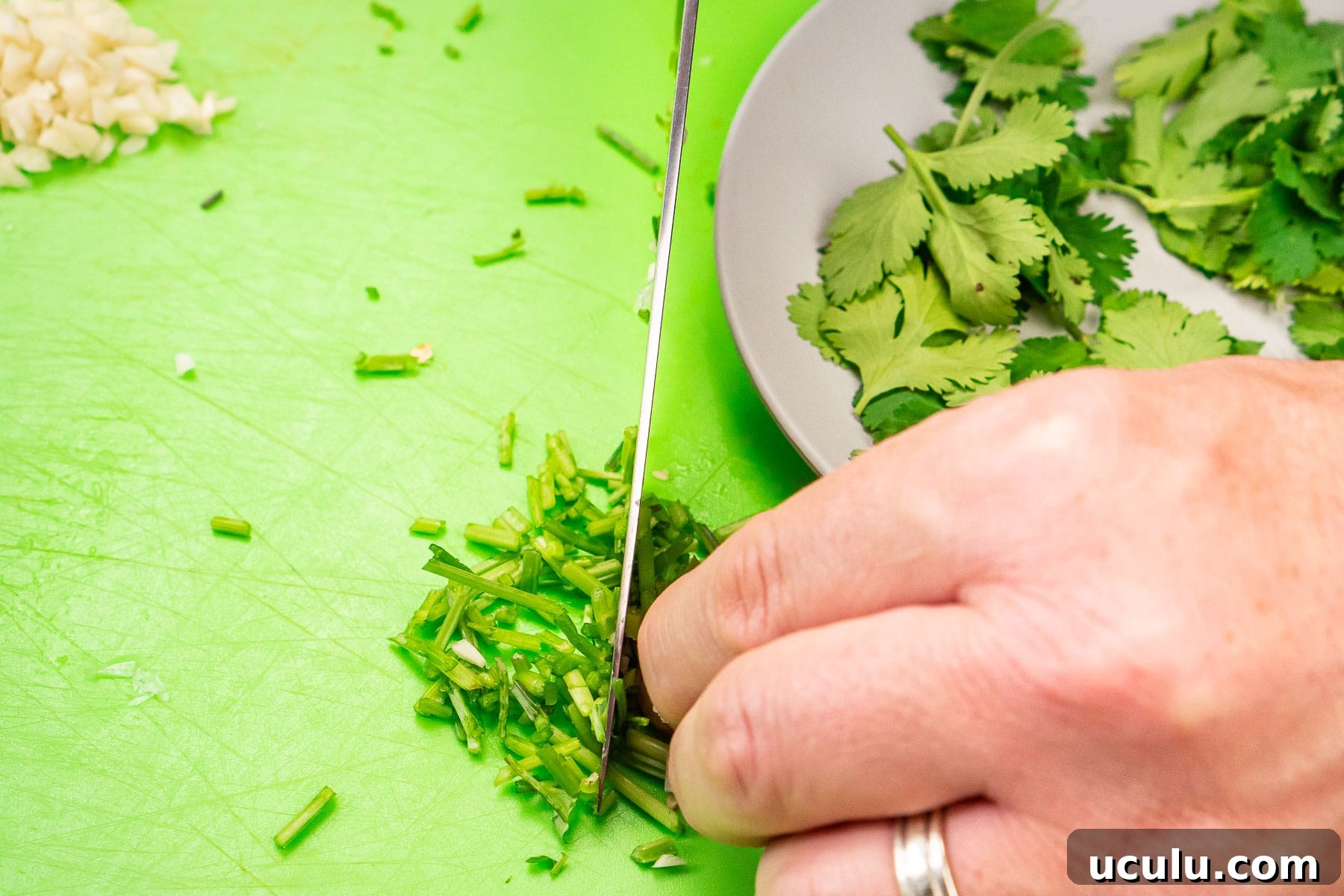 Indian Mushroom Bhaji Recipe | Flavorful Mushroom Curry Guide 16 Chopping coriander stems with a knife on a green chopping board