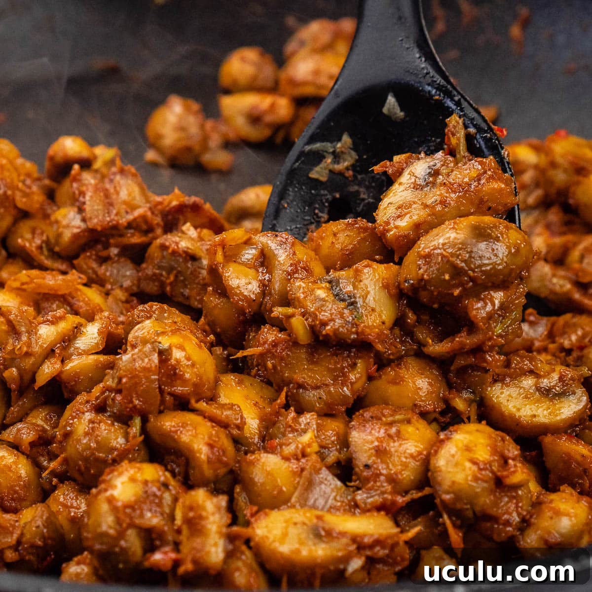 Indian Mushroom Bhaji Recipe | Flavorful Mushroom Curry Guide 23 Stirring mushroom bhaji curry with a black cooking in a pan