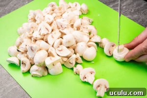 Indian Mushroom Bhaji Recipe | Flavorful Mushroom Curry Guide 4 Chopping up closed cup mushrooms on a green chopping board