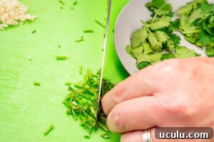 Indian Mushroom Bhaji Recipe | Flavorful Mushroom Curry Guide 5 Chopping coriander stems with a knife on a green chopping board