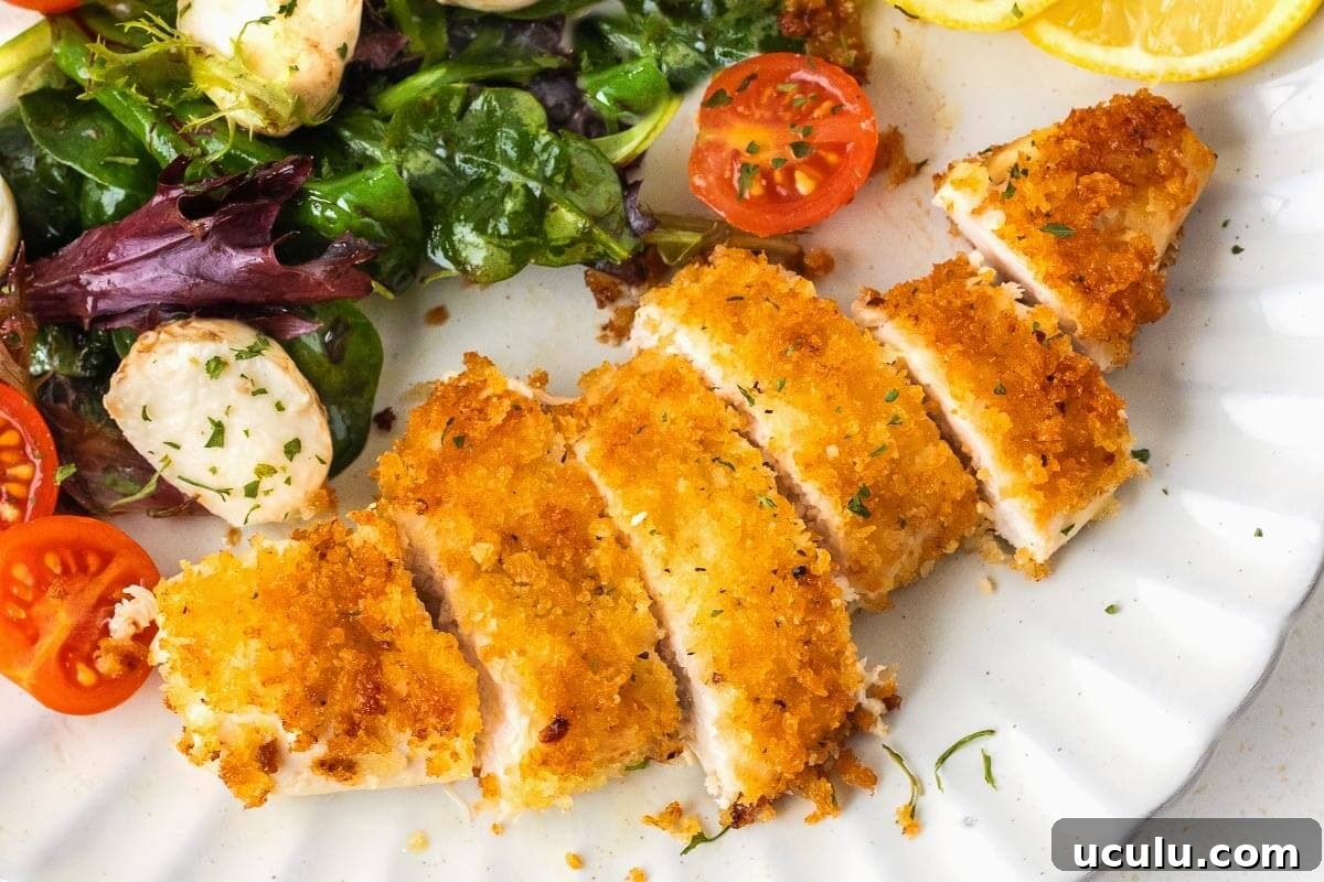 Crispy Pan-Fried Chicken Cutlets on a white plate with salad