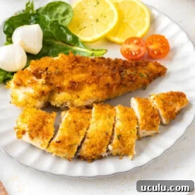 Crispy Pan-Fried Chicken Cutlets on a white plate with salad