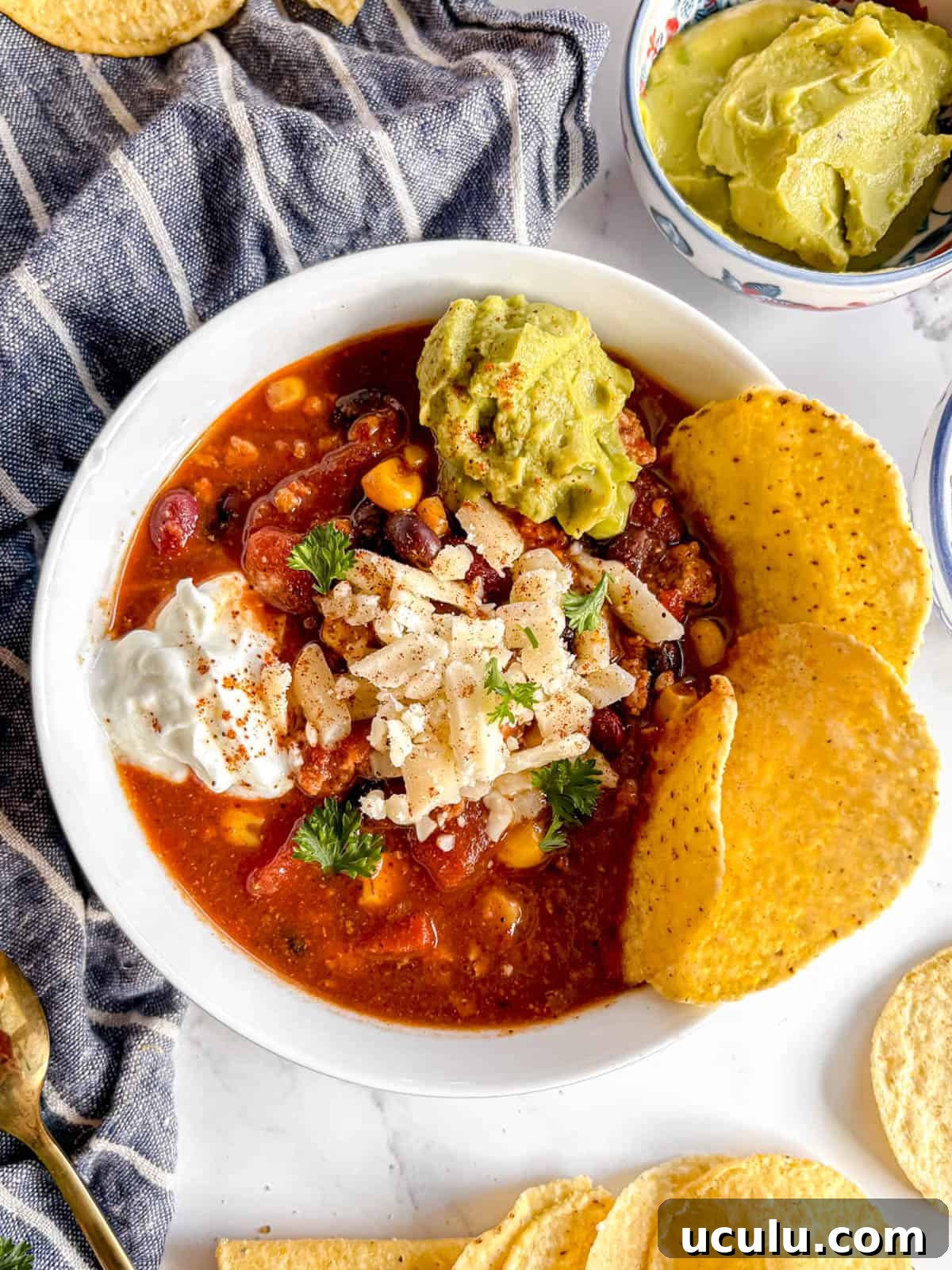 Crockpot turkey chili in a bowl with guac, cheese and greek yogurt on top.