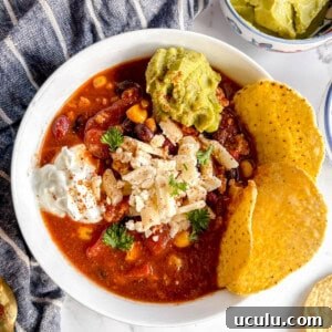 Crockpot turkey chili in a bowl with guac, cheese and greek yogurt on top.