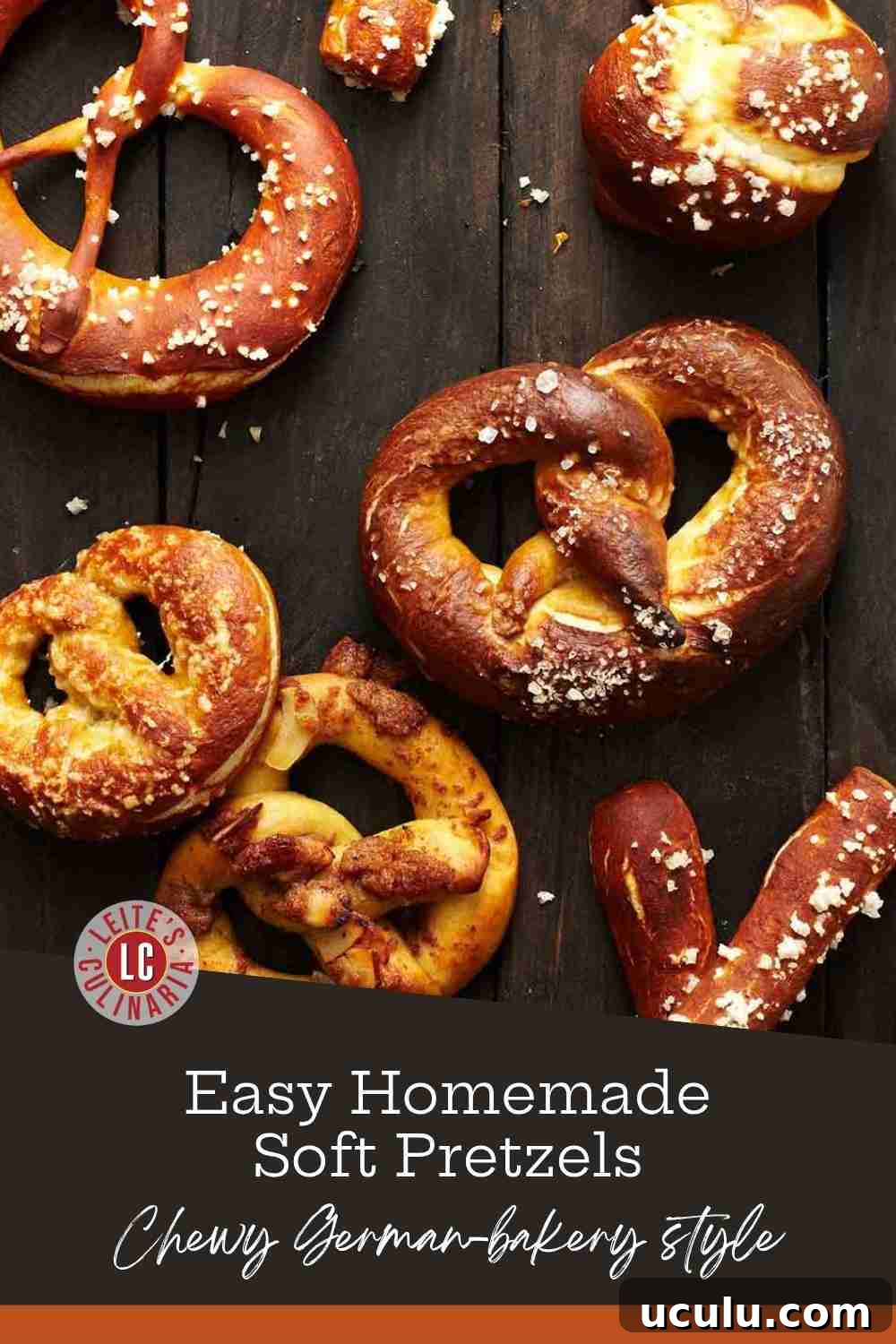 Deep mahogany soft pretzels and pretzel bites covered in coarse sea salt on a dark, rustic wooden surface.