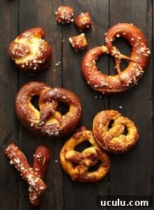 Soft pretzels of assorted shapes and sizes on a wooden surface.